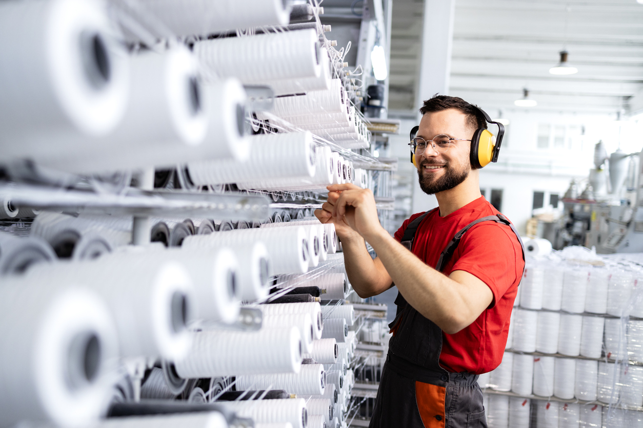 Medewerker die de grootschalige naaimachine controleert